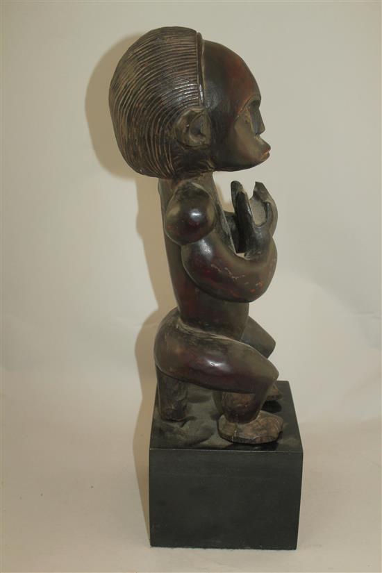 A West African carved hardwood figure of a seated male, overall 22in.